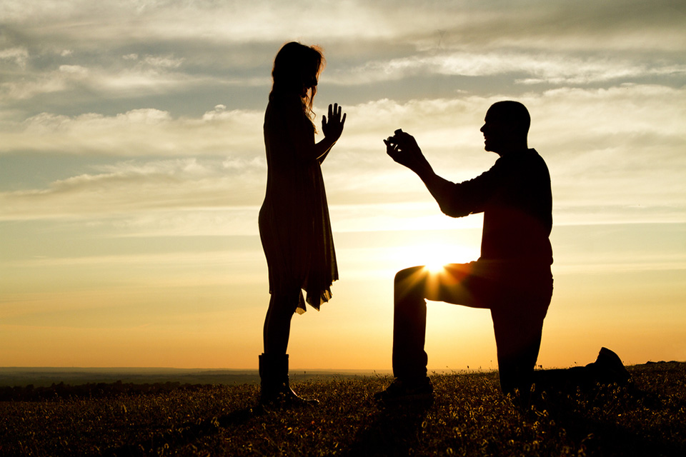 a man proposing to a woman in front of a sunset